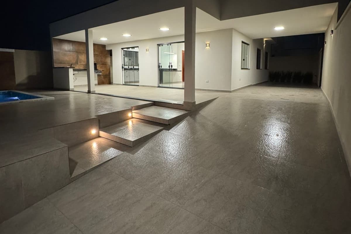 Área externa da Casa 1 à noite, com piscina à esquerda e a varanda gourmet iluminada.
