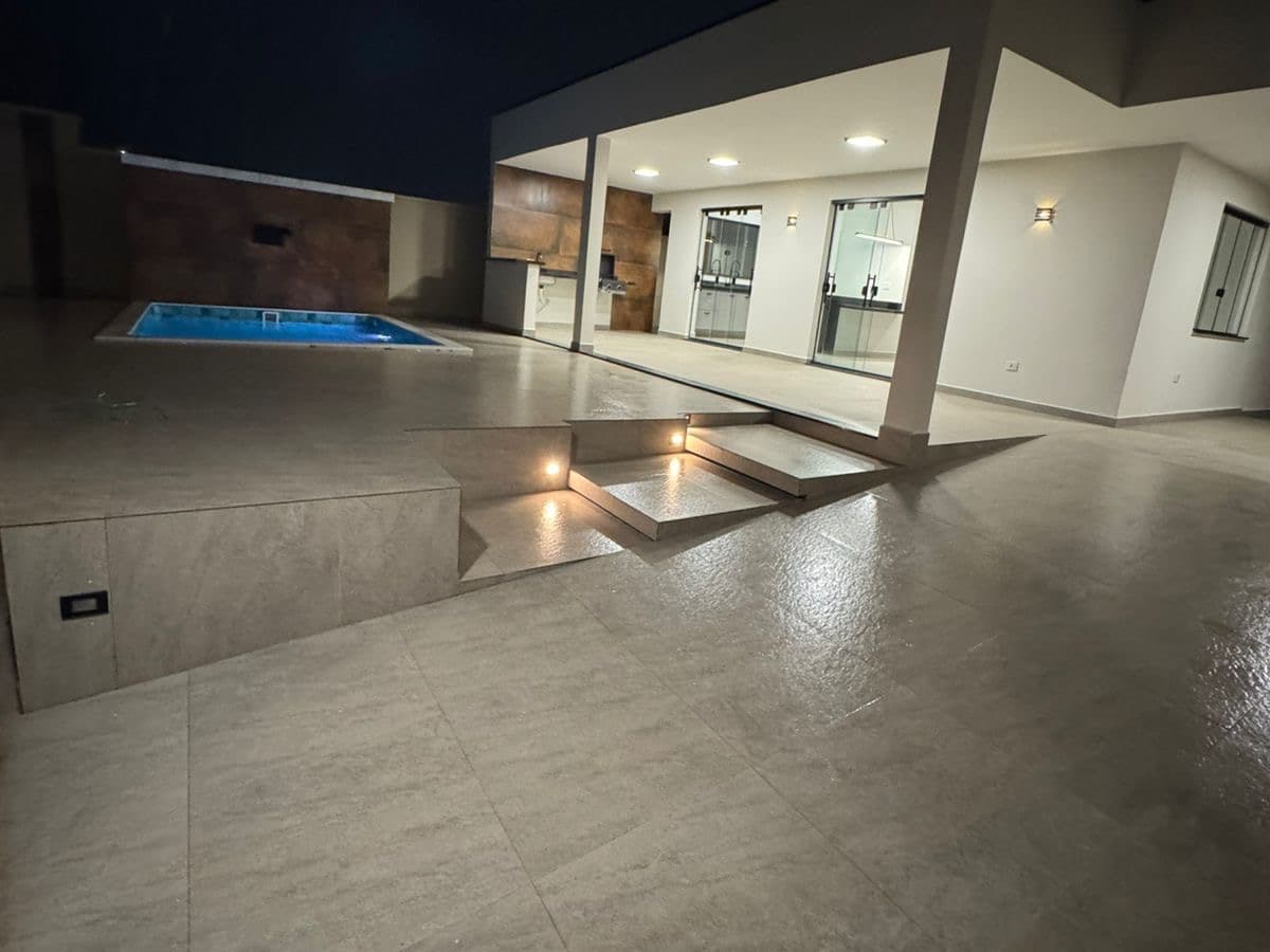 Área externa da Casa 1 à noite, com a piscina e o piso em porcelanato.