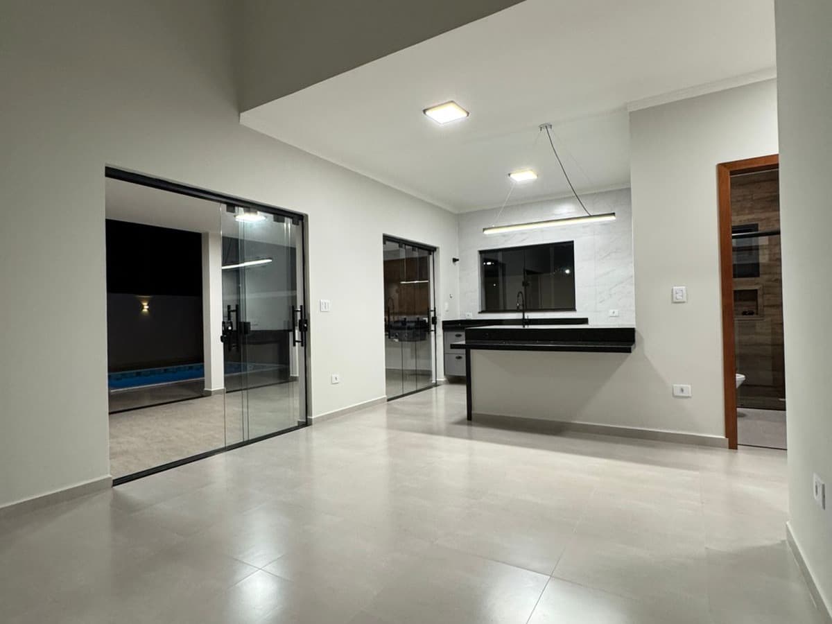 Sala da Casa 1 integrada à cozinha, com portas de vidro para a área da piscina.