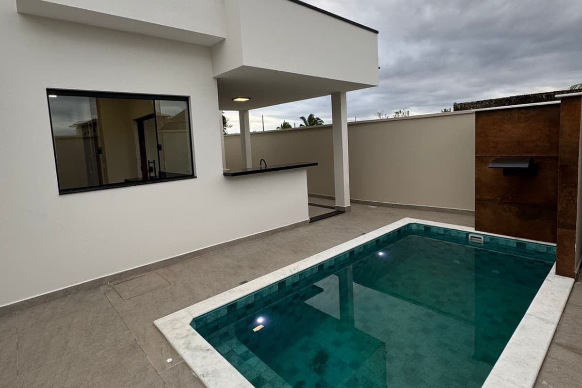 Fachada lateral da Casa 2 com a piscina e a varanda gourmet, à luz do dia.