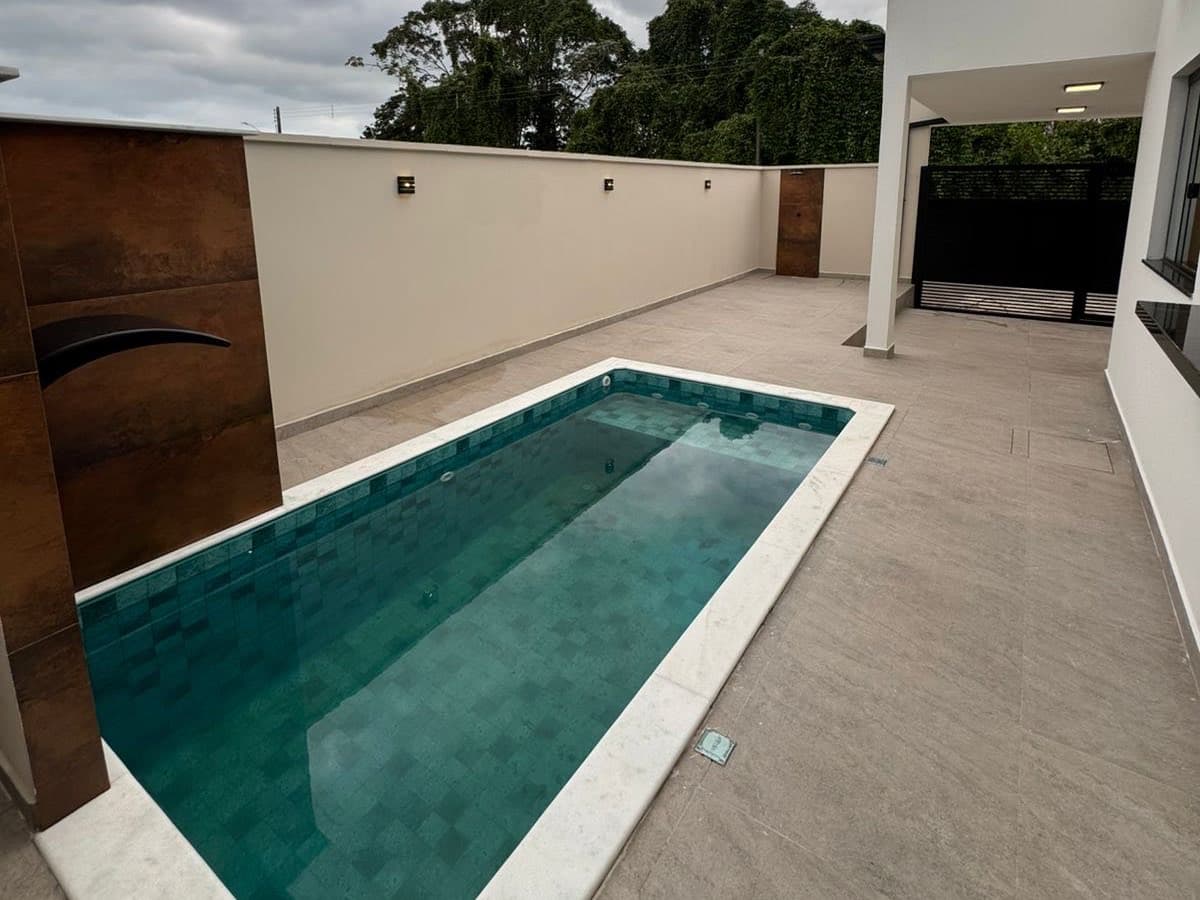 Piscina da Casa 2 com revestimento esmeralda e mata ao fundo.