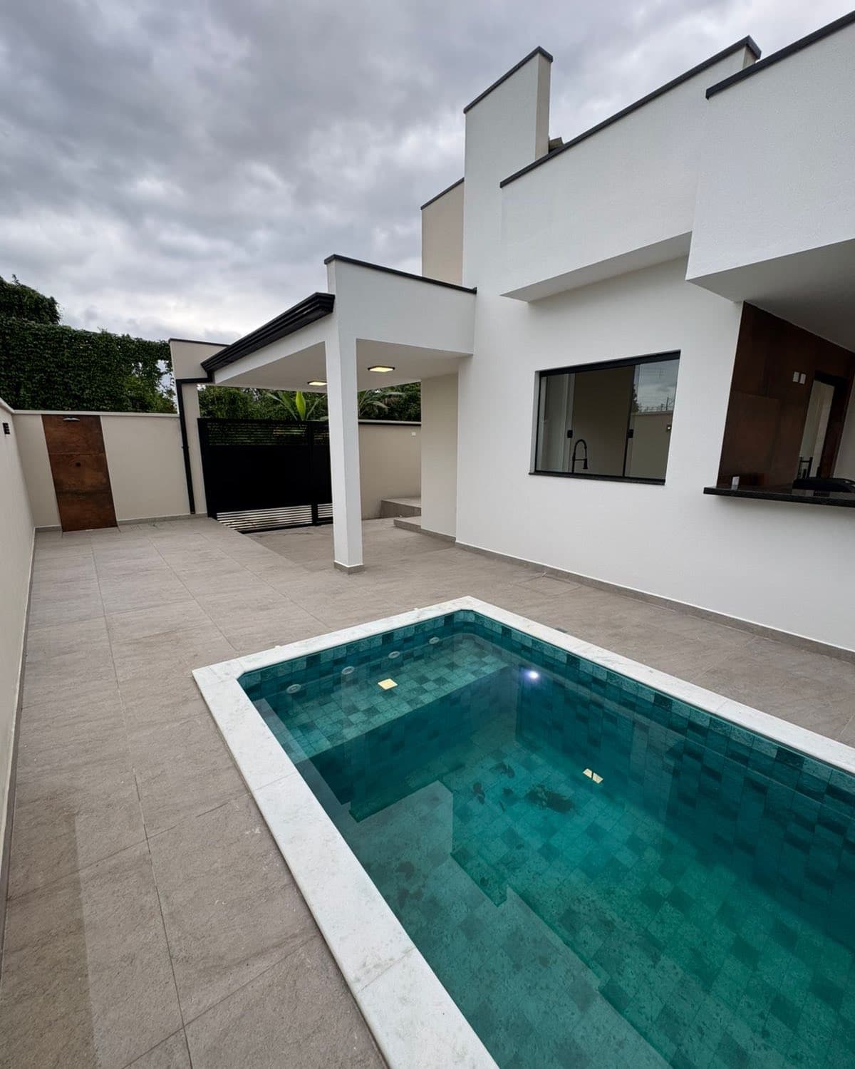 Casa 2 vista da área externa, com a piscina de revestimento esmeralda em primeiro plano.